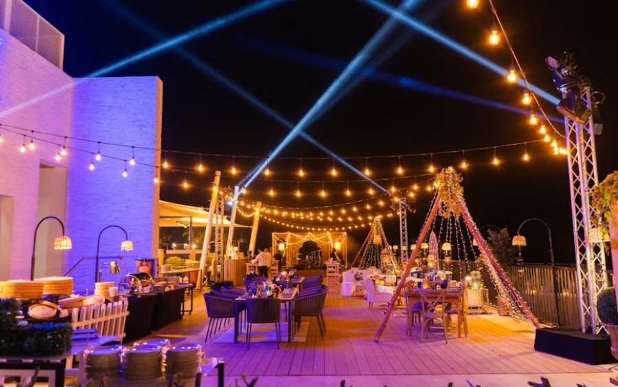 Idées d'événements pour entreprise : installation en soirée sur un rooftop avec guirlandes lumineuses et traiteur